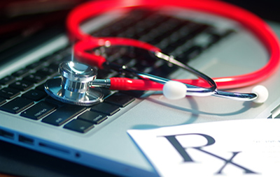Stethoscope and Rx papers laying on top of laptop keyboard